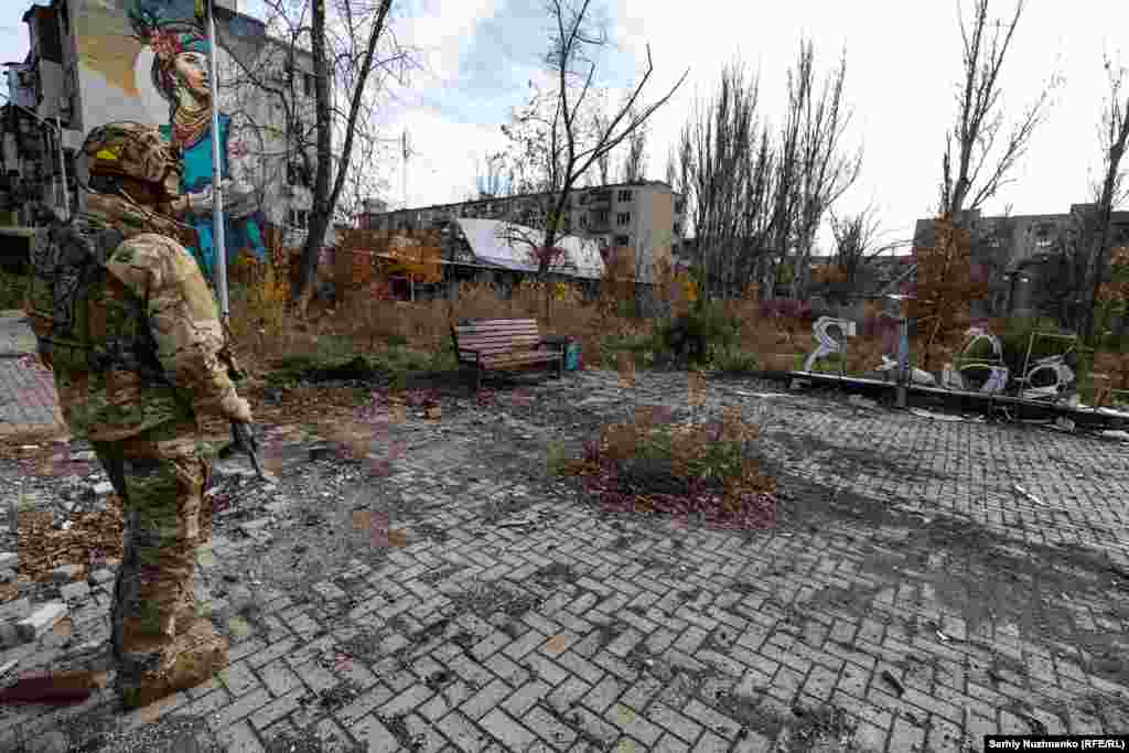 Un soldat ucrainean din Avdiivka stă lângă lucrarea din oțel, deteriorată, cu inscripția „I Love Avdiivka”, în noiembrie 2023, când fotoreporterul RFE/RL Serhi Nujnenko a vizitat orașul pentru ultima dată înainte de ocuparea acestuia. Armata rusă a cucerit Avdiivka în februarie 2024. Etapa finală a bătăliei a durat mai mult de cinci luni - din octombrie 2023.