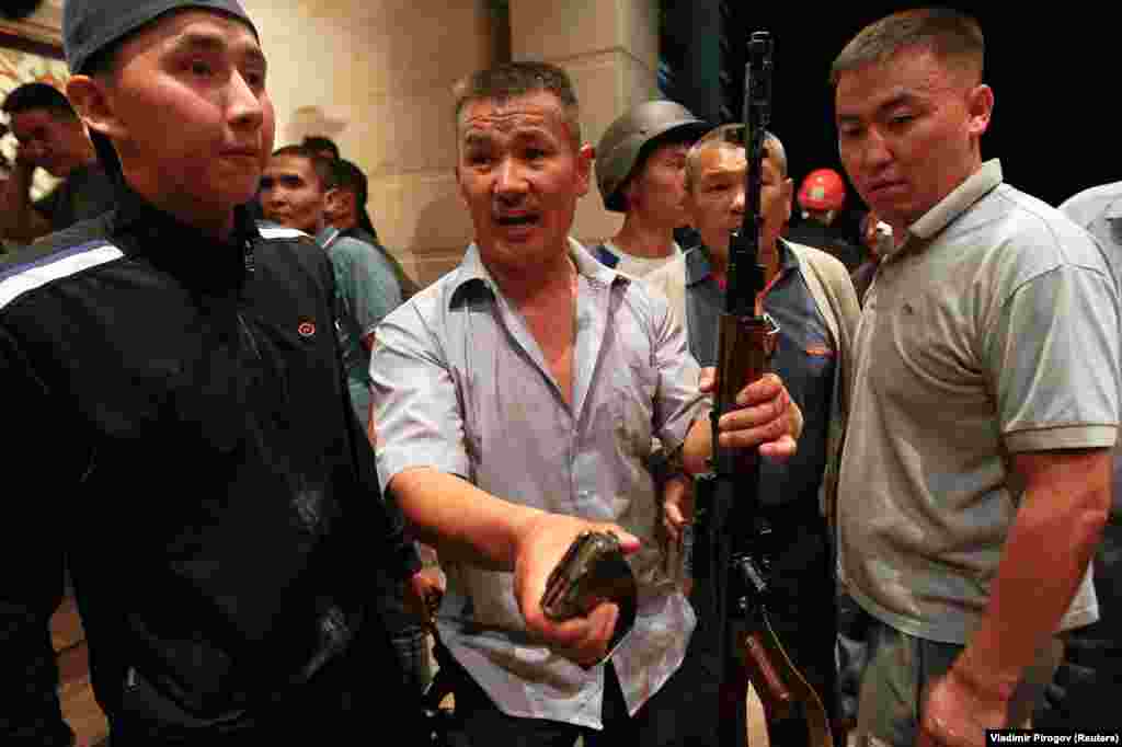 Supporters of Atambaev brandish an assault rifle and a clip of ammunition. 
