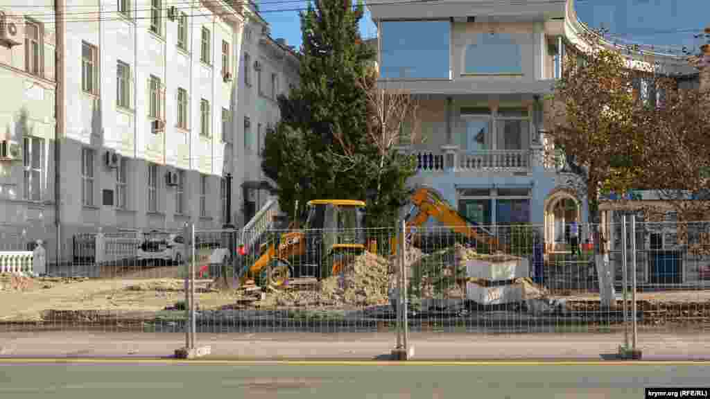 Экскаватор копает грунт на тротуаре возле торгового центра «Диалог»