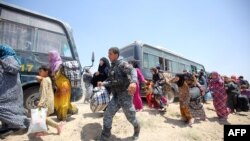 Iraqi forces help civilian families in Iraq's Anbar Province after they fled Fallujah during a major operation by pro-government forces to retake the city from Islamic State militants.