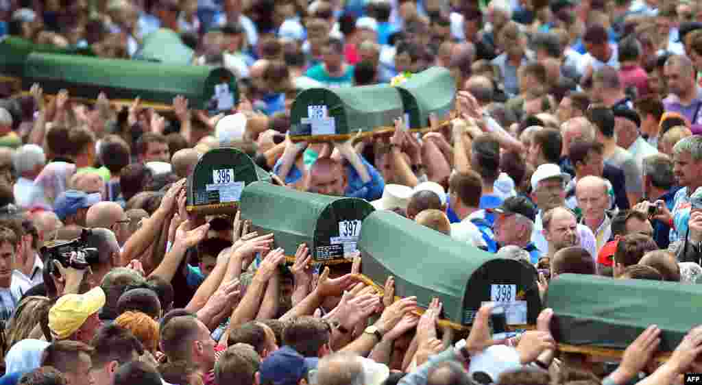 Bosnian Muslims carry caskets containing the bodies of people killed in the 1995 Srebrenica massacre as they prepare for a mass burial during a memorial ceremony in the village of Potocari on July 11, the 18th anniversary of the killings. (AFP/Elvis Barukcic)