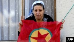 A Kurdish woman waves a PKK flag from her house in Diyarbakir, Turkey.