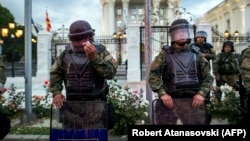 A Macedonian police officer tries to remove red paint from his helmet's visor after protesters threw balloons filled with colored paint during an antigovernment protest in Skopje on June 6.
