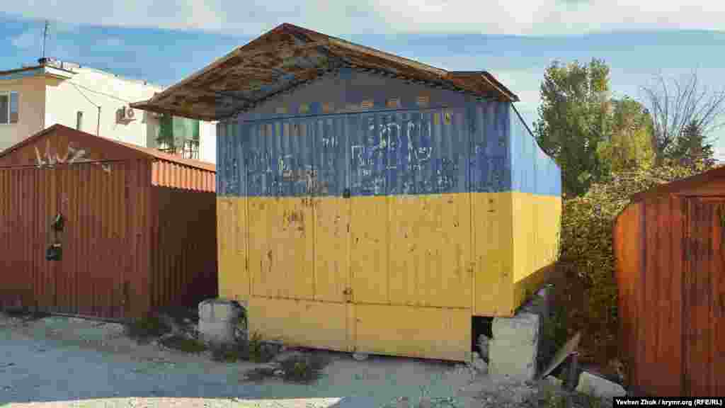 Синьо-жовтий гараж у селі Сахарна Головка, 2019 рік. Як повідомляв кореспондент Крим.Реалії, раніше гараж стояв на імпровізованій «центральній площі». Після анексії Криму він став «заважати» російській владі Криму – господар був змушений його прибрати вглиб місцевого гаражного кооперативу, проте перефарбовувати не став