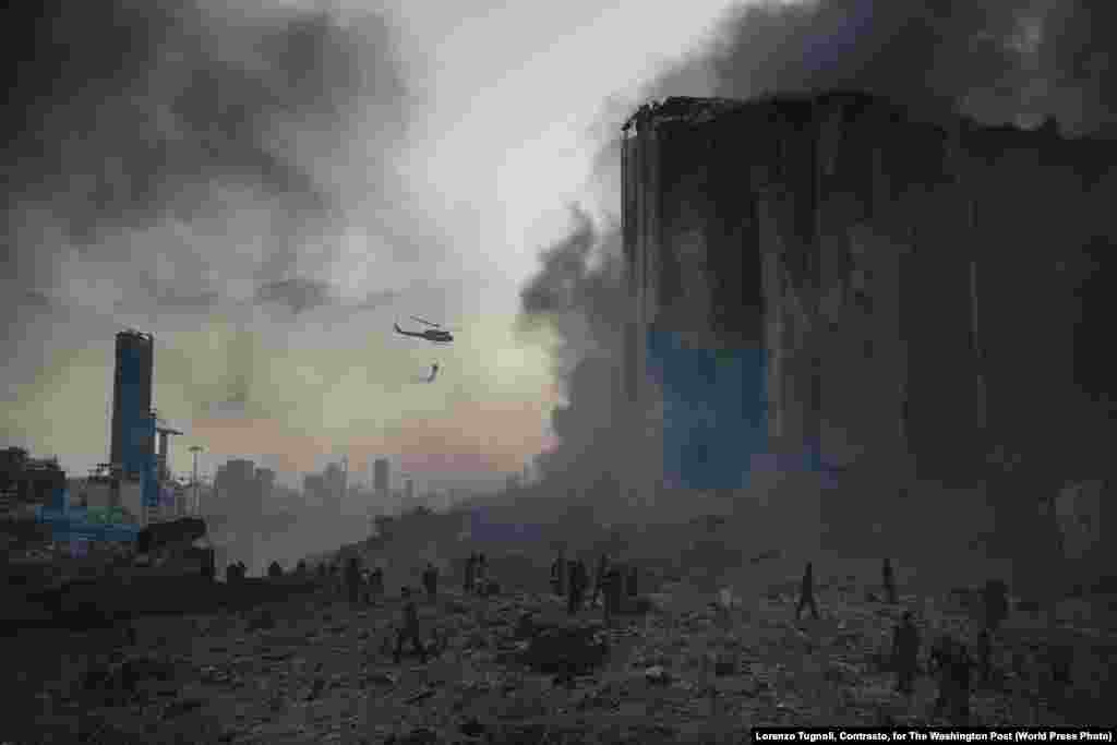 Снимок из фоторепортаж «Взрыв в порту Бейрута». На месте катастрофы работают пожарные (4 августа 2020). Около десяти пожарных погибли на месте взрыва. Первое место в категории «Срочные новости, фоторепортаж», автор – Лоренсо Тугноли