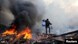 A man walks amid burning remains of barricades on Independence Square in Kyiv on February 21.