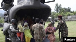 U.S. and Pakistani service members help flood victims exit a U.S. Army helicopter in Khwazakhela