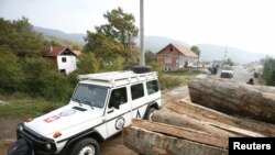 A NATO KFOR vehicle passes by a partially removed roadblock near the village of Zupce in the tense northern Kosovo region.
