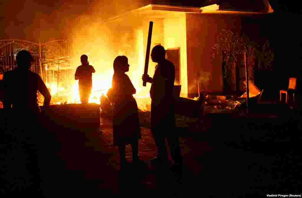 A fire rages in the compound as supporters of the ex-president arm themselves with sticks. 