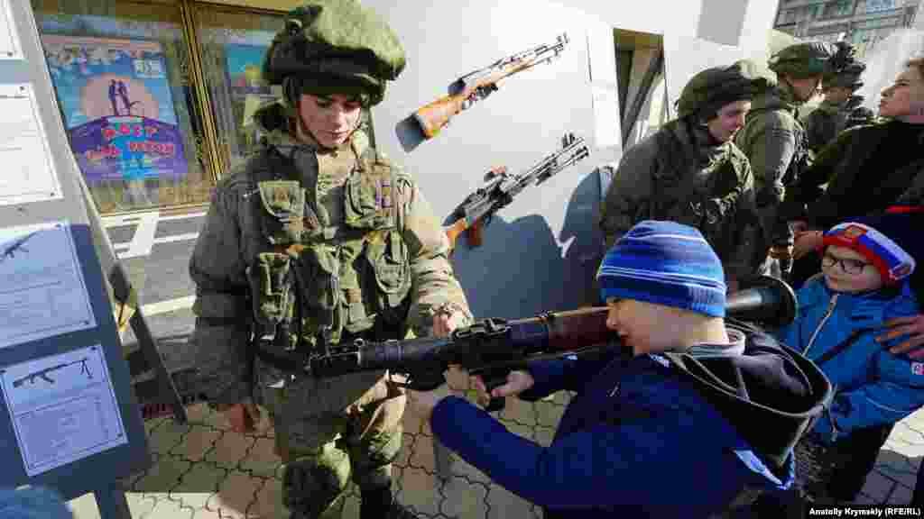 23 февраля, Симферополь. Люди в российской военной форме показывают детям оружие и дают его им в руки. Правозащитники указывают на то, что милитаризация образования и детства, пропаганда войны среди детей – это нарушение Конвенции о правах ребенка, которая обязывает воспитывать детей в уважении к нормам международного гуманитарного права