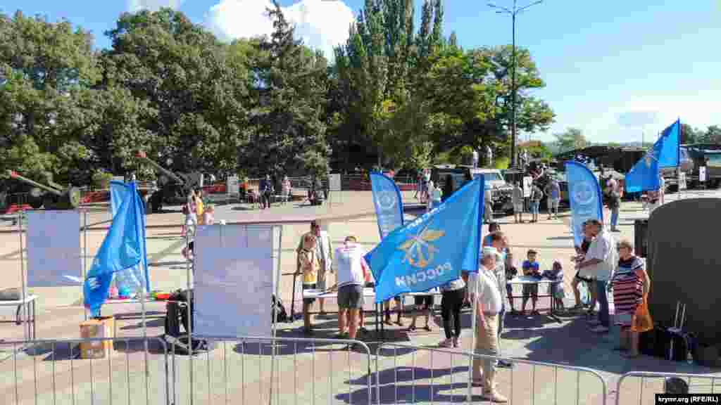 Територія, на якій розгорнута виставка російської військової техніки, повністю огороджена по периметру. За найближчими до огорожі столами – зовсім юні відвідувачі виставки, зі зброєю в руках