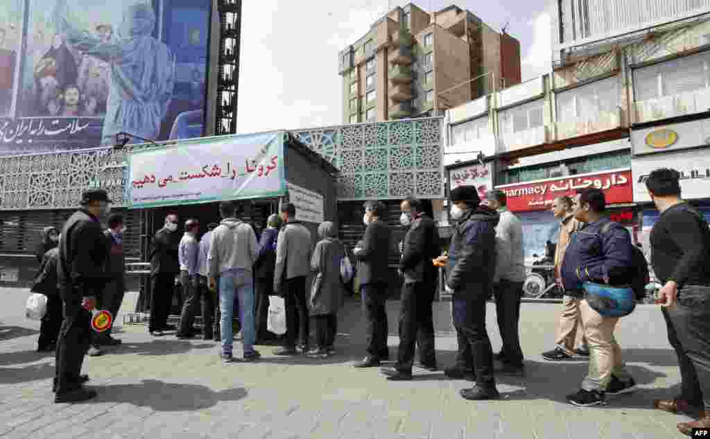 People wait in line in Tehran to receive packages for precautions against the spread of the disease. The goods were provided by the Basij, a militia loyal to Iran's Islamic rulers.