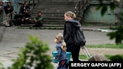Украинка с ребенком выходят из разрушенного дома, архивное фото