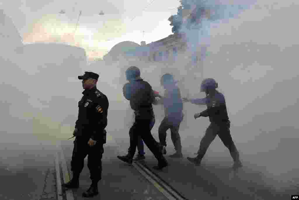 A protester is led away through clouds of smoke in St. Petersburg. 