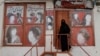 A woman wearing a niqab enters a beauty salon where the ads of women have been defaced by a shopkeeper in Kabul.