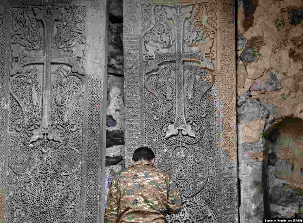 A man prays in front of Dadivank's large cross stones. 