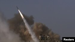 Members of Iran's Revolutionary Guard look at a surface to surface missile as it is launched during military exercises.