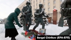 A woman places a red carnation near a picture of Russian pilot Roman Filipov, who was shot down in Syria, in front of the Russian Defense Ministry in Moscow on February 6.