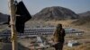 Un luptător taliban stă de gardă deasupra unei tabere de refugiați afgani repatriați din Pakistan, în mai 2025.