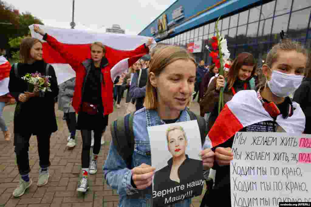 A supporter holds up a photo of Maryya Kalesnikava saying, "Bring back our Masha!!!" on a march to Independence Avenue in central Minsk. The woman beside her is holding a sign that says: "We want to live another way."