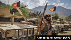 Armed men supporting the fight against the Taliban stand with their weapons and Humvee vehicles in Bazarak in Afghanistan's Panjshir Province on August 19.