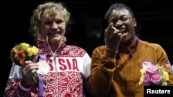 Claressa Shields (right) of the United States poses with her gold medal accompanied by silver medallist Nadezda Torlopova of Russia during the presentation ceremony for the women's middleweight boxing competition at the London Olympic Games on August 9.