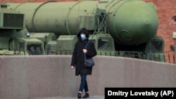 A woman wearing a face mask during a coronavirus lockdown walks past a Russian intercontinental ballistic missile launcher displayed at the Artillery Museum in St. Petersburg.