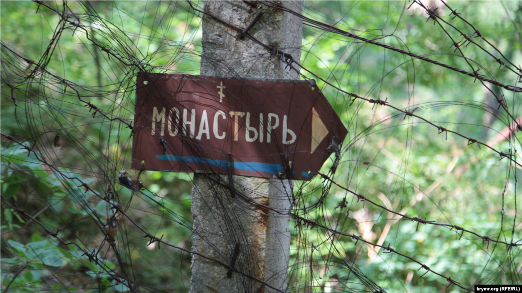 Вузька стежка, що веде до монастиря, обгороджена колючим дротом. За нею – територія військових частин