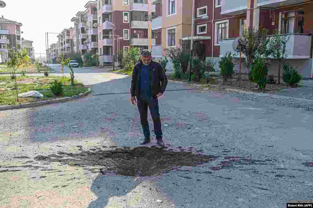 A man looks at a crater blasted into a road in Tartar, near the front line of the ongoing conflict, on October 18.
