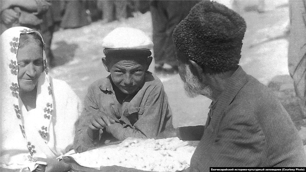 Уличный торговец. Бахчисарай, 1920-ые. Большинство ремесленников сами продавали изготовленный ими товар в собственных лавках, но крымский город невозможно представить без базара. Существовала и разносная торговля – коробейники, обвешанные ожерельями, цепочками, платьями, чубуками и другими предметами ходили по городским улицам