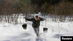 Оксана Ширшова несет коромысло с двумя ведрами воды из реки Терёл в селе Верхняя Бирюса, расположенном в тайге вблизи Красноярска