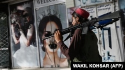 A Taliban fighter walks past a beauty salon with images of women defaced using spray paint in Kabul on August 18, days after the militant group seized the Afghan capital.