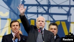 U.S. Senator John McCain (center) waves to pro-European-intergration protesters during a mass rally at Independence Square in Kyiv on December 15.