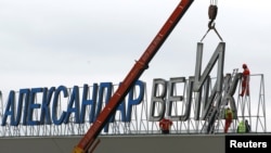 Workers dismantle the "Alexander the Great" sign at Macedonia's Skopje airport on February 24.