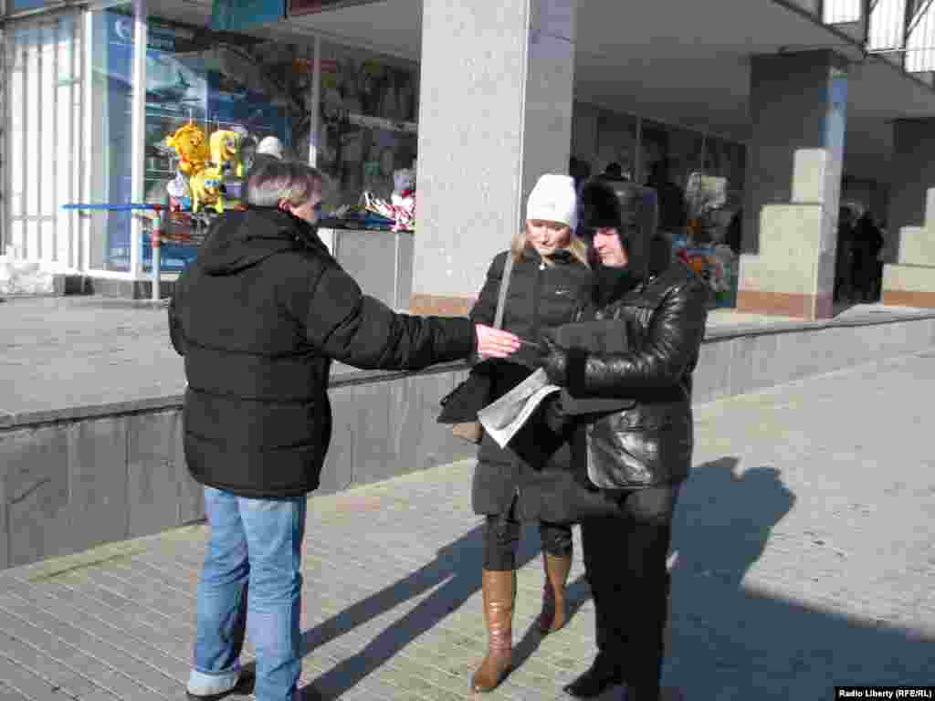 Активист раздает визитки движени  'Белая  лента'