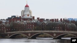 Un pod peste râul Charles, care curge prin fața Universității Harvard din Cambridge, văzută în depărtare, 15 aprilie 2025