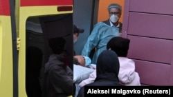 Medical specialists carry Russian opposition leader Aleksei Navalny on a stretcher into an ambulance on their way to the airport before his medical evacuation to Germany in Omsk on August 22, 2020.