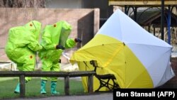 Investigators in green bio-hazard suits examine the site where Sergei Skripal and his daughter Yulia were found poisoned in Salisbury, England.