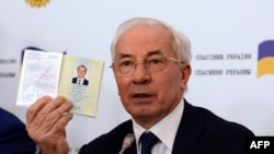 Николай Азаров с украинским паспортом в руках во время пресс-конференции в Москве.