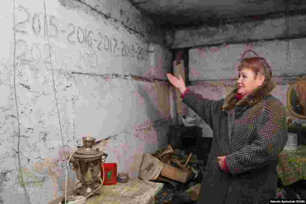 A woman points to dates written on the wall in a bomb shelter in Yasynuvata. The dates refer to New Year's parties that she and other local people celebrated there.