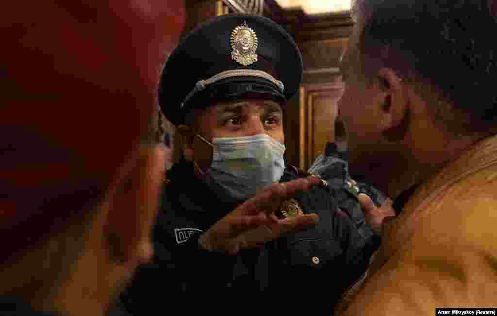 A policeman speaks with protesters inside Armenia's parliament building. 
