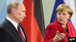 German Chancellor Angela Merkel speaks next to Russian President Vladimir Putin during a press conference in Berlin