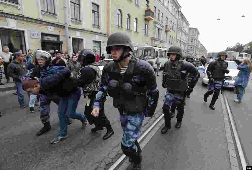 Police wearing ballistic helmets advance up a street in St. Petersburg. 