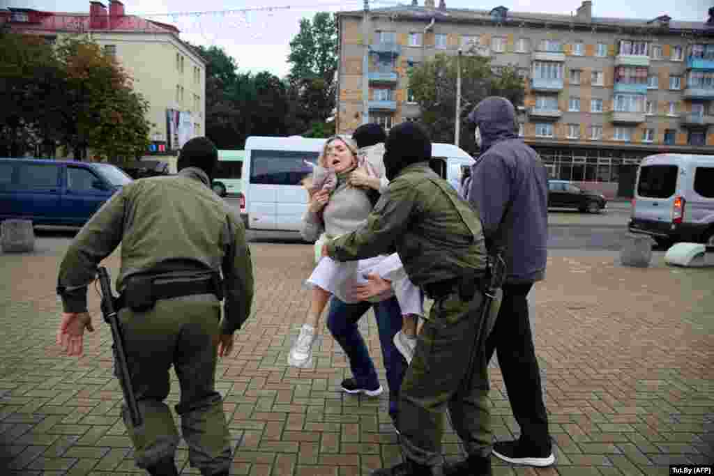 Masked officers carry away one of Kalesnikava's supporters.