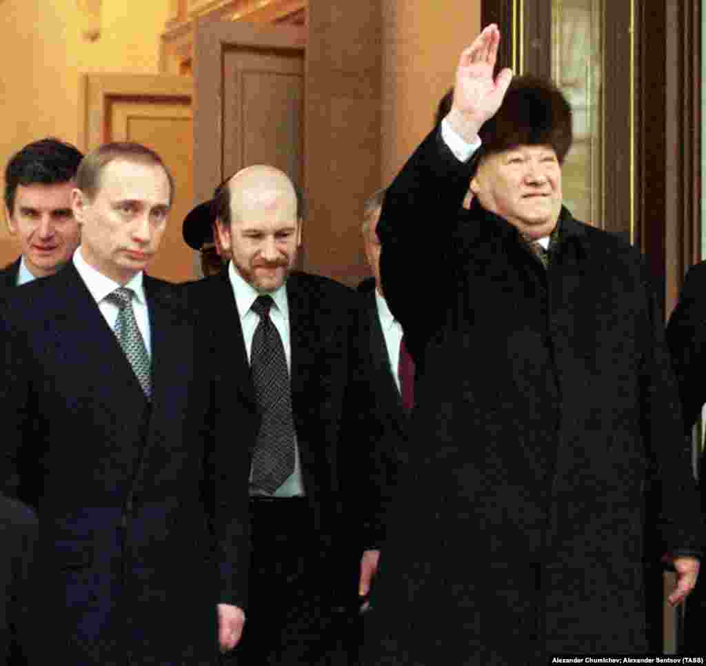 Ельцин машет рукой, стоя рядом с Владимиром Путиным 31 декабря 1999 года. В тот день Ельцин передал президентское кресло Путину после почти десятилетнего пребывания у власти. Ельцин оставил свой пост, как говорит часть специалистов, глубоко непопулярным – в основном из-за экономических трудностей, которые угрожали стране во время его президентства. Но другие считают, что он предотвратил потенциальную гражданскую войну в России во время масштабных политических изменений, которые он наблюдал после краха Советского Союза. Ельцин умер в апреле 2007 года в возрасте 76 лет  
