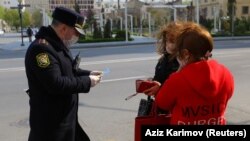 An Azerbaijanii police officer checks the documentation of two women in Baku amid a coronavirus lockdown in the city.