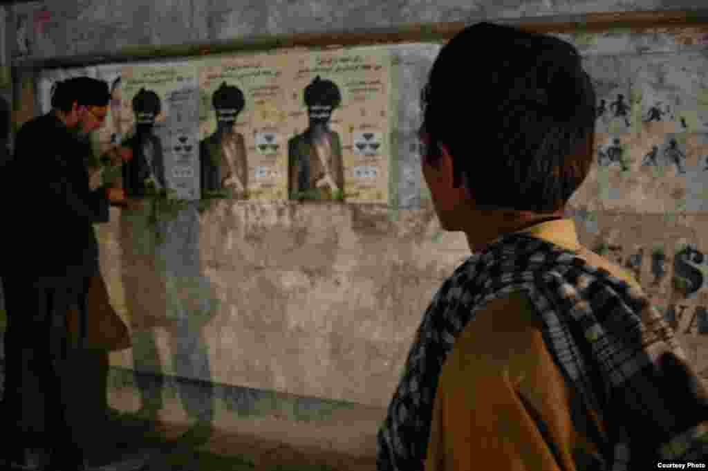 Aman Mojadidi secretly puts up fake posters during the night.